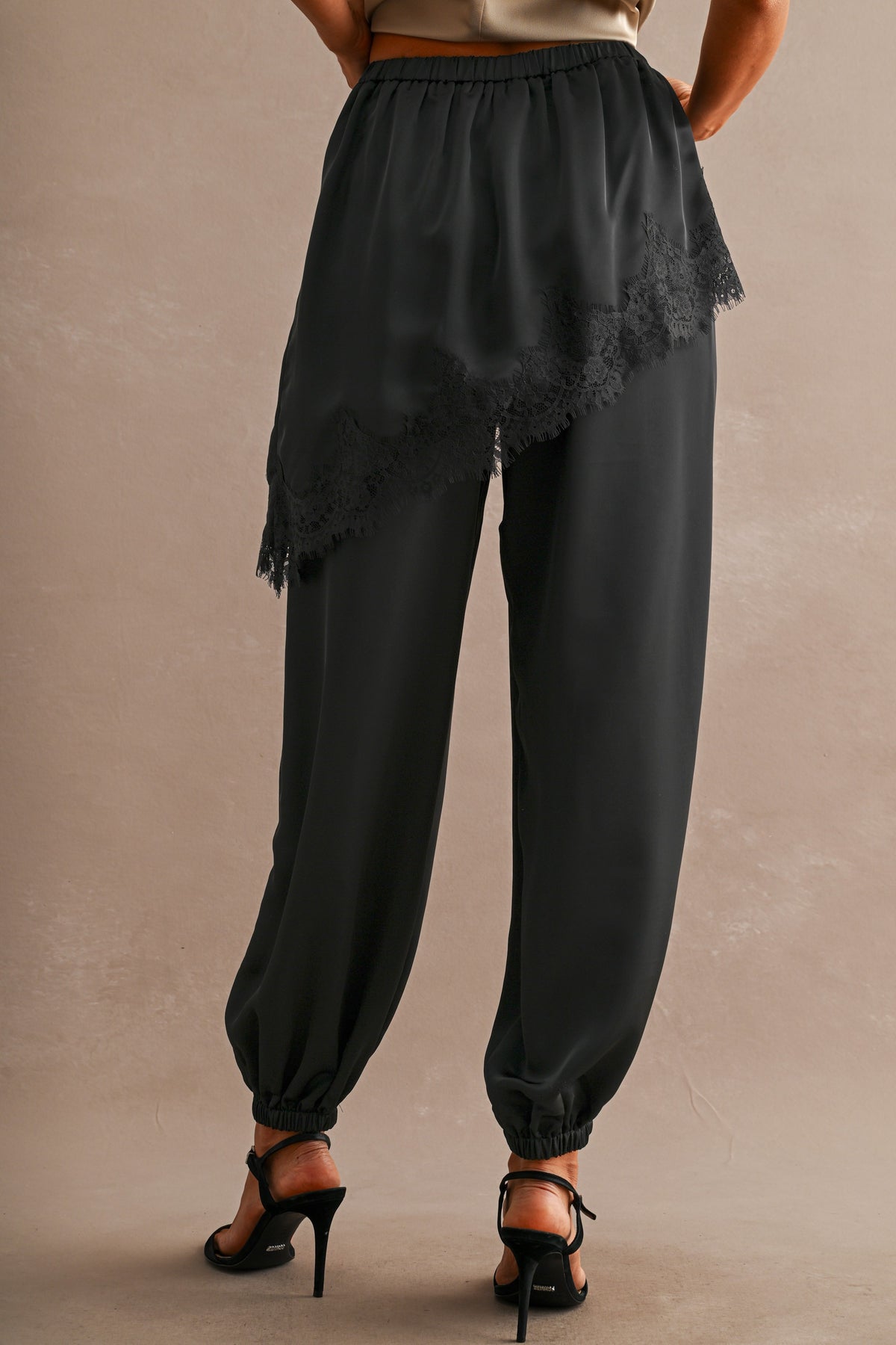 Back view of black satin joggers with lace-trimmed overlay panel