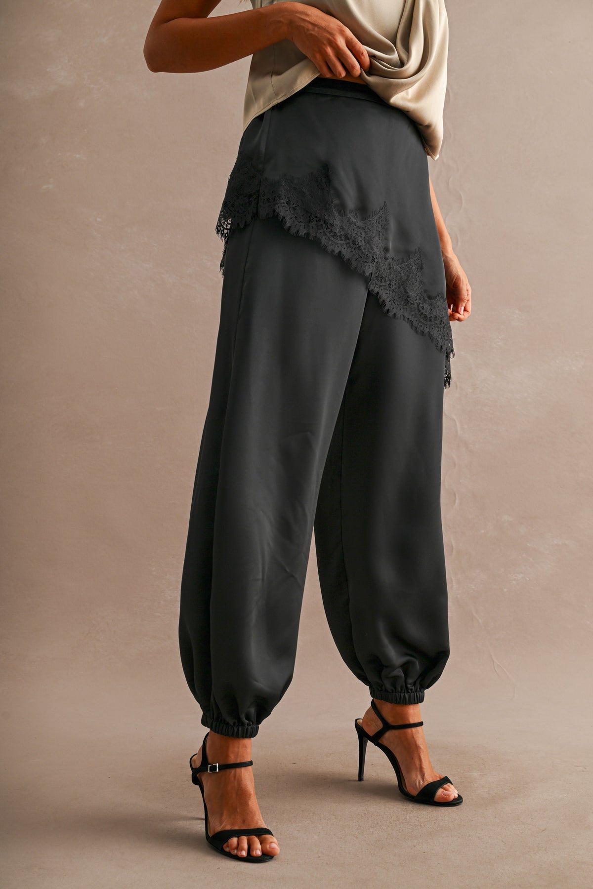 Side view of black satin joggers with eyelash lace overlay panel
