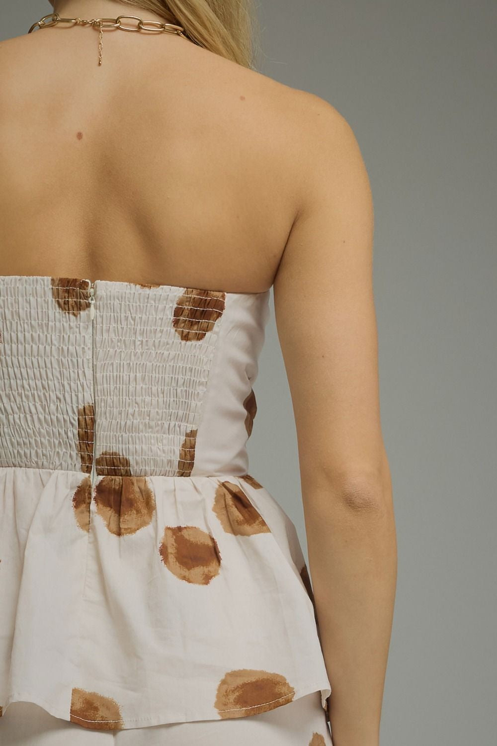 Vista posterior de prenda blanca sin tirantes con estampado marrón y espalda fruncida
